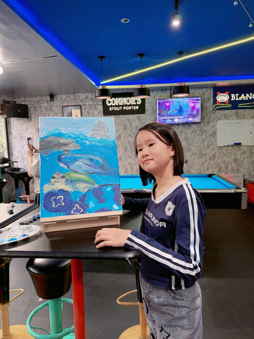 A young customer posing beside her completed ocean painting